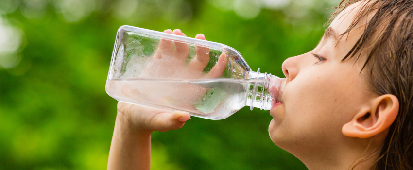 Girl drinking clean tap water from transparent plastic bottle